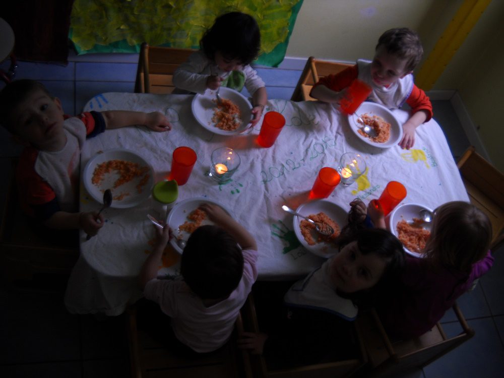 Un'immagine che ritrae mobilia, tavolo, bambino, stoviglie e cibo.